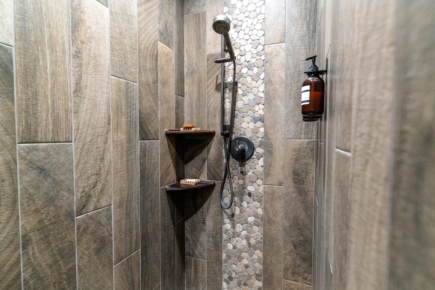 Beautiful Views — wood-grain tile shower with pebble-stone accent strip and rainfall head