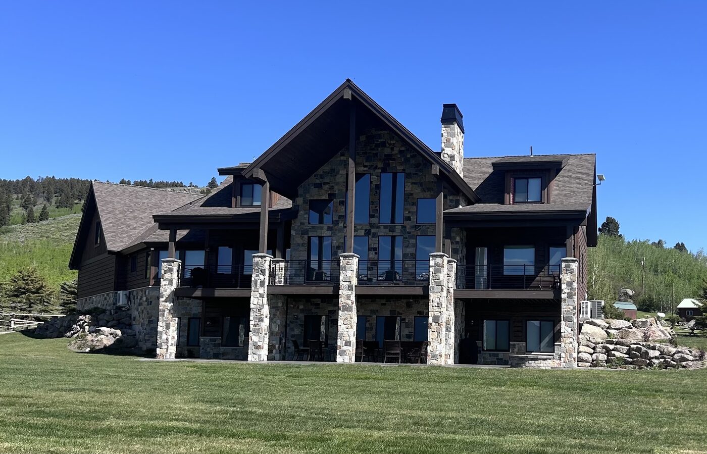Beautiful Views — rear exterior on Henry's Lake with stone-column balconies and lawn
