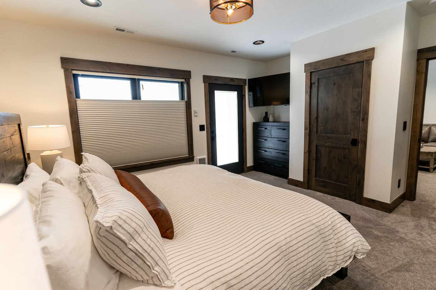 Lodge at Cutthroat Landing — king bedroom with black bed frame, neutral linens, and balcony door
