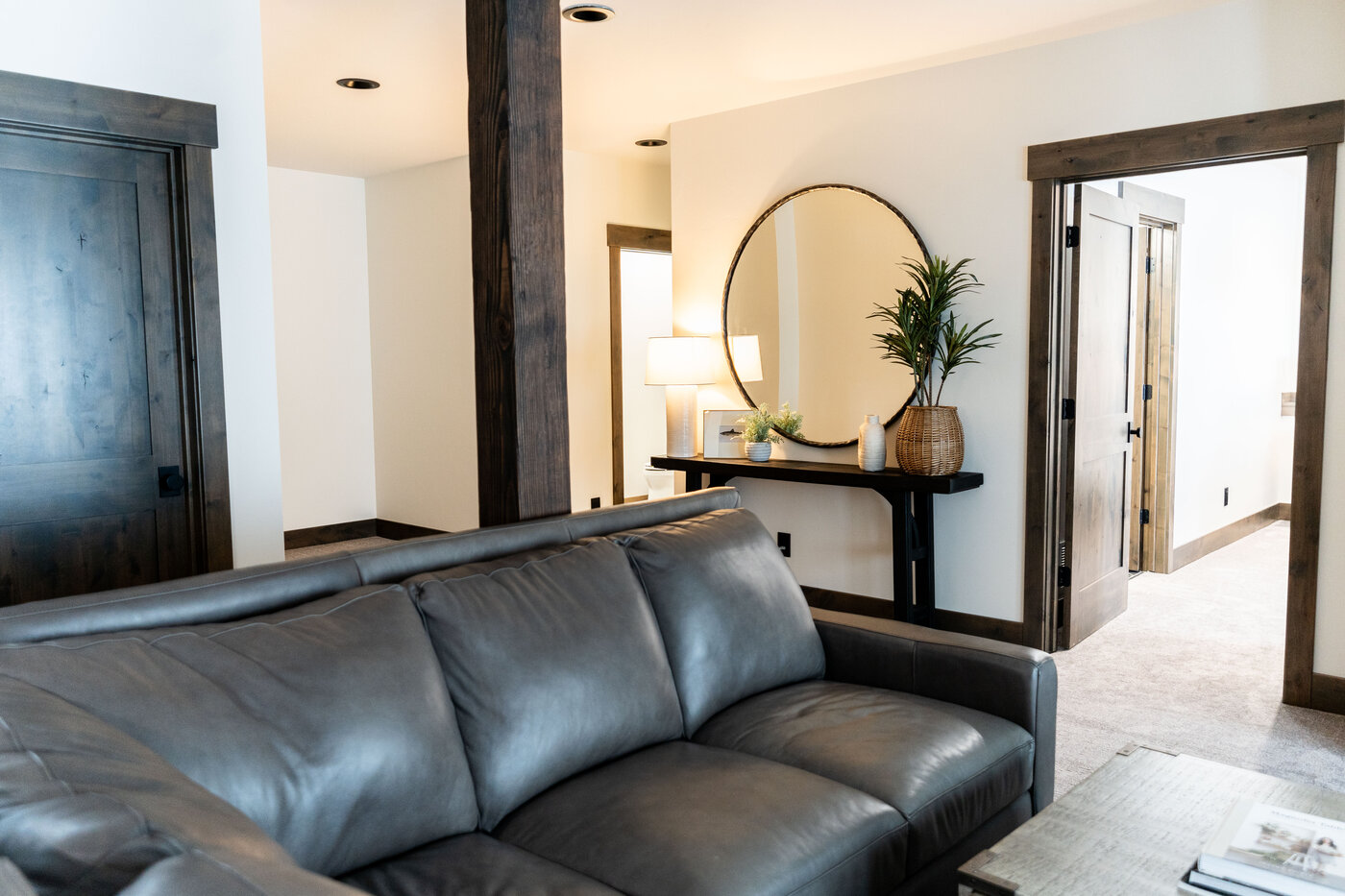 Lodge at Cutthroat Landing — sitting area with gray leather sofa and round wood-framed mirror