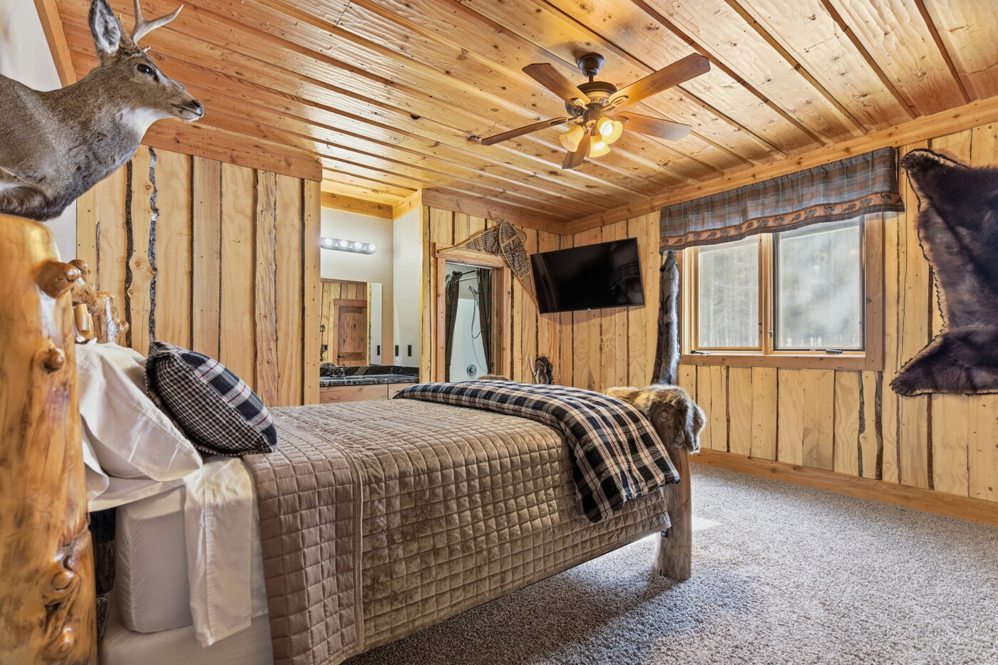 Riverfront Wildlife Lodge — queen bedroom with whitetail buck mount and tartan blanket