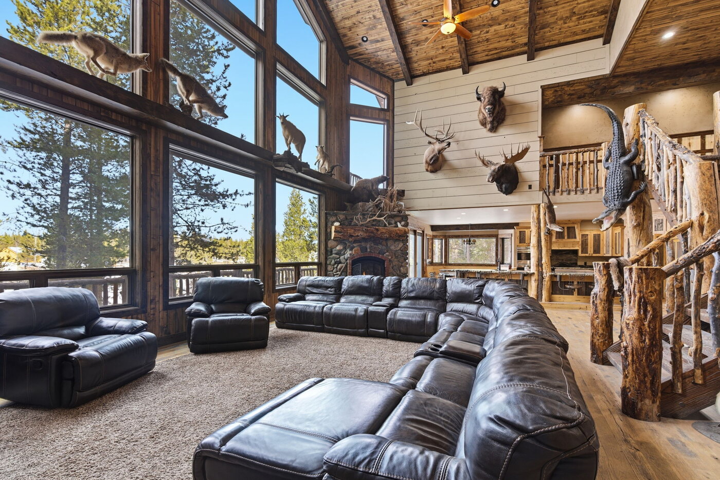 Riverfront Wildlife Lodge — great room with leather sectional and floor-to-ceiling forest views