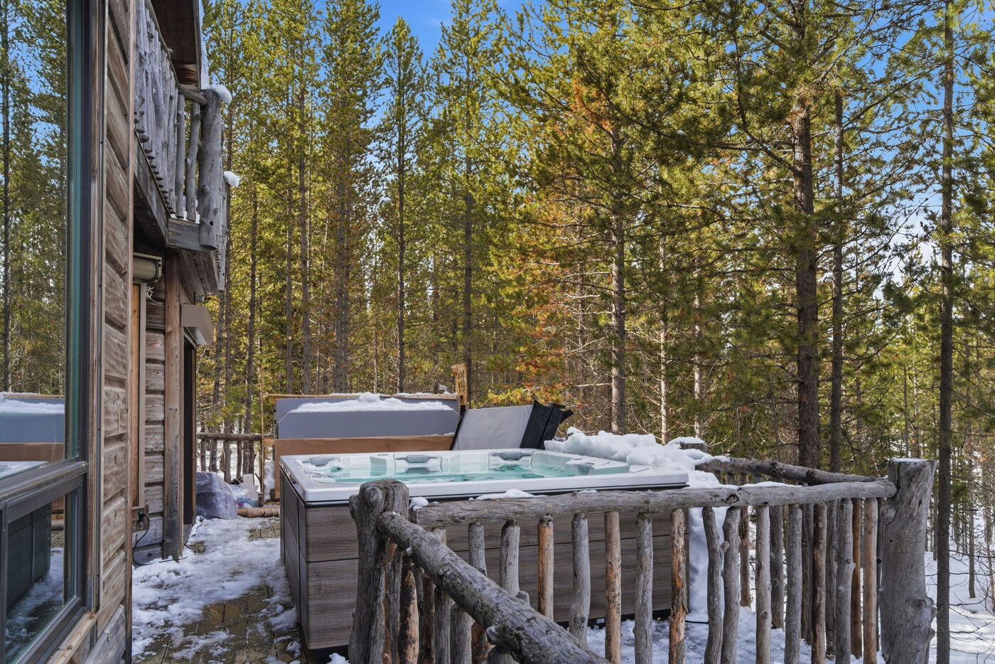 Riverfront Wildlife Lodge — hot tub looking out into the snowy pine forest from the deck