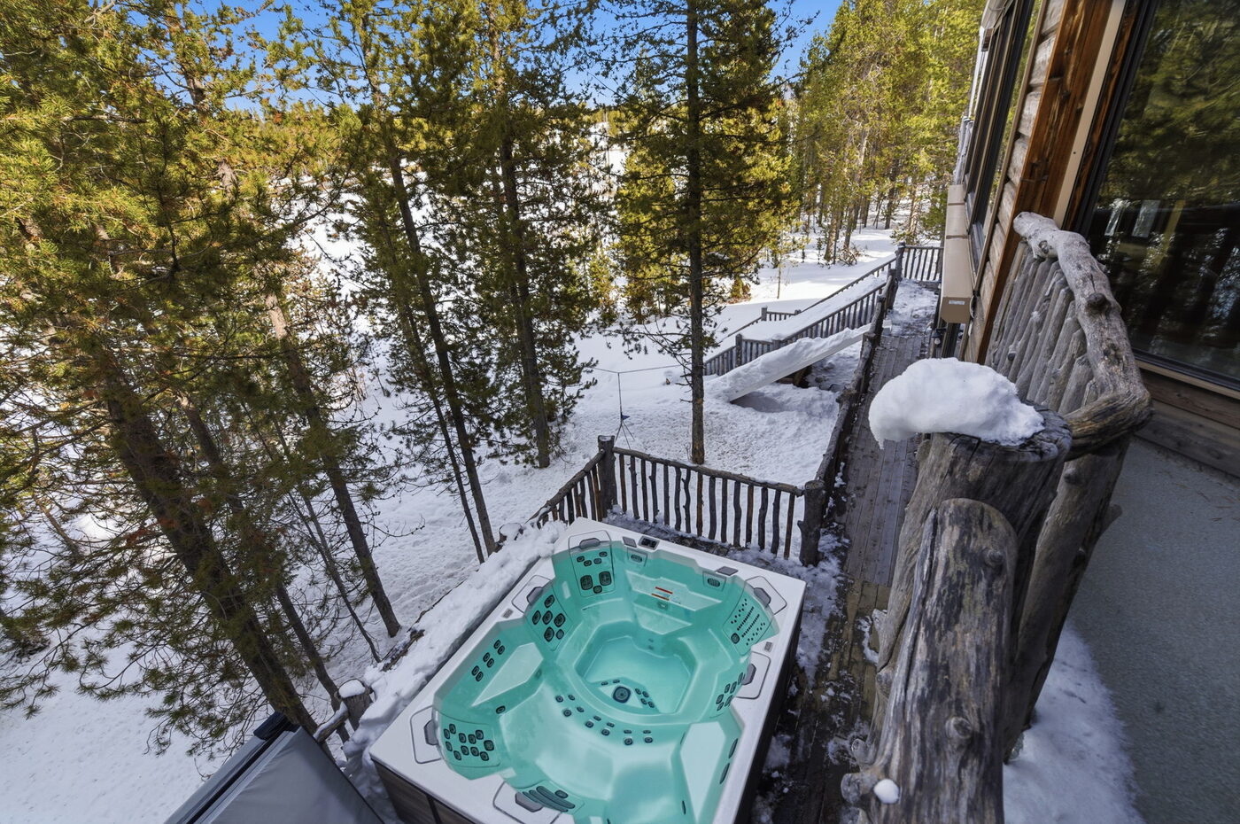 Riverfront Wildlife Lodge — hot tub from above with snow-covered Big Springs forest beyond
