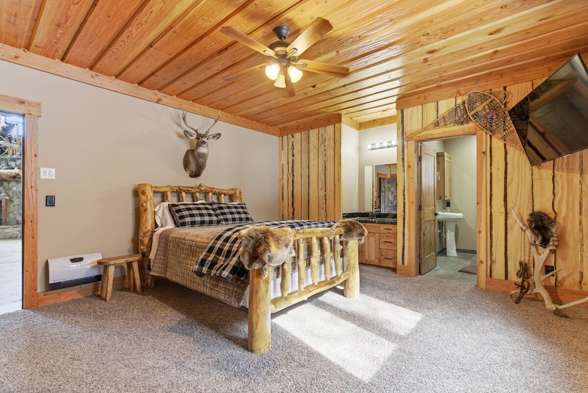 Riverfront Wildlife Lodge — hunting-themed bedroom with rustic wood walls and trophy details