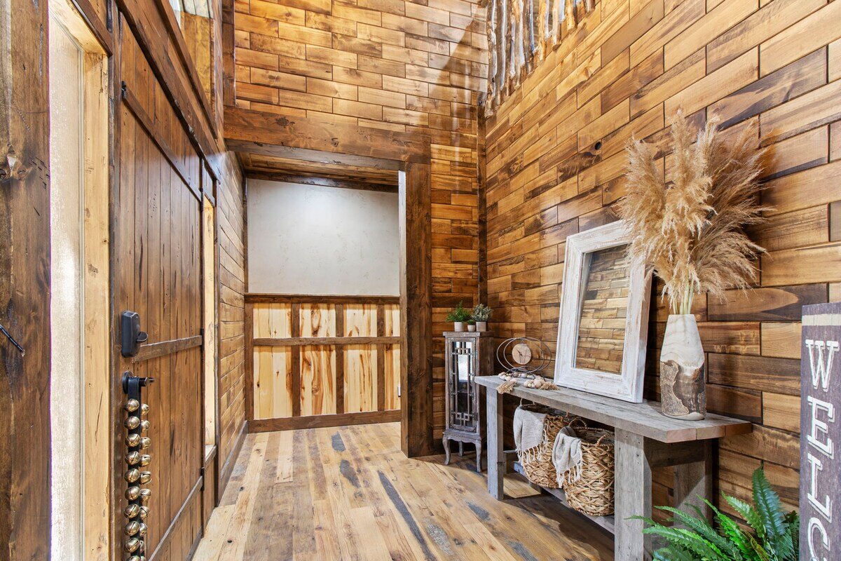 Riverfront Wildlife Lodge — primary suite with reclaimed wood walls and forest views