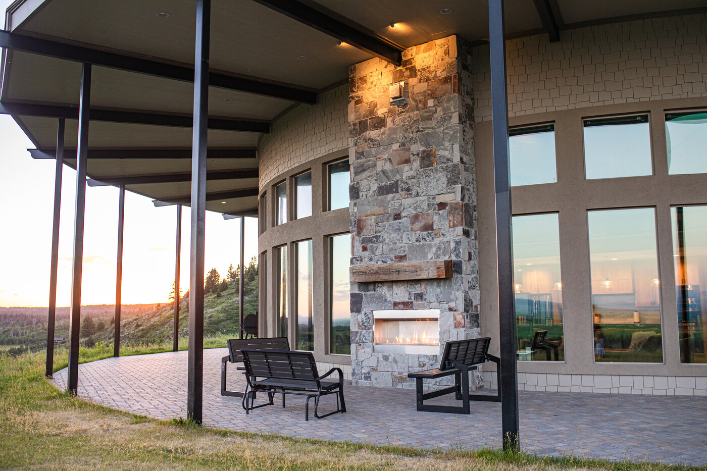Teton View Retreat — Both Domes — covered porch with outdoor stone fireplace at golden hour