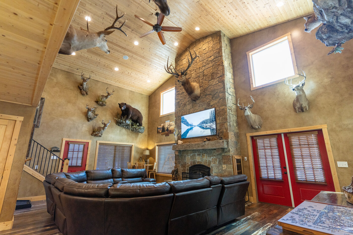 Trails End Lodge — cathedral ceiling great room with stone fireplace, mounted bull elk, and surrounding taxidermy