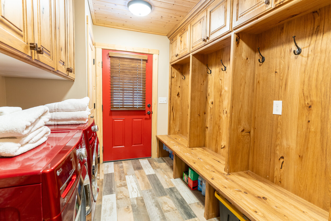 Trails End Lodge — mudroom with red back door, custom hickory cubbies, and red front-load washer-dryer
