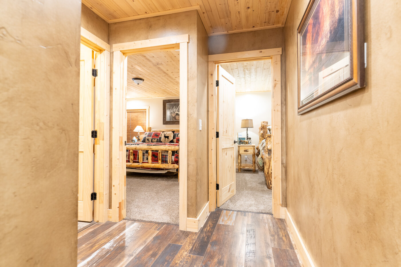 Trails End Lodge — hallway looking into two bedrooms with rustic plank flooring