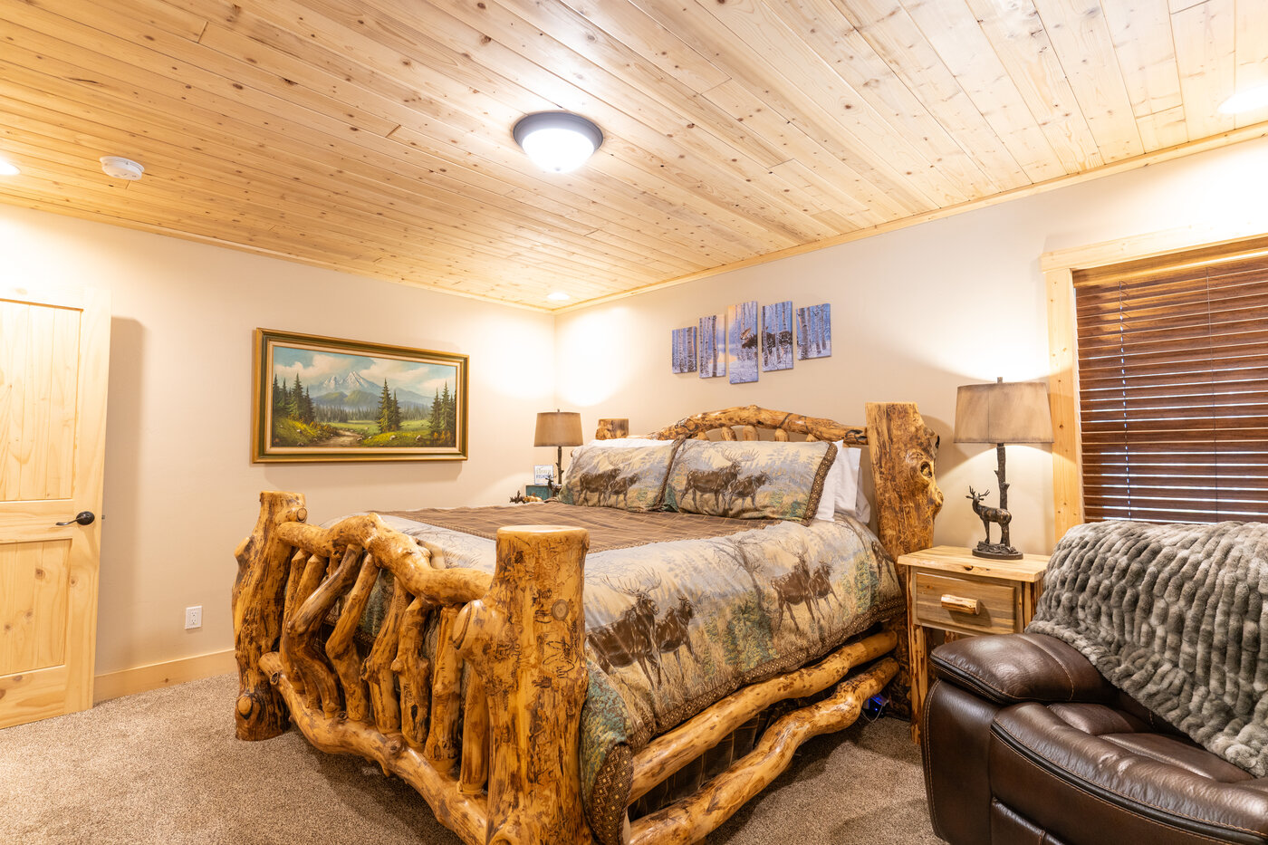 Trails End Lodge — bedroom with carved log king bed and framed Tetons painting