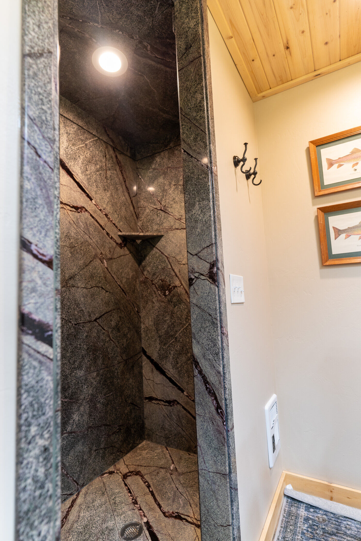 Trails End Lodge — custom stone-look shower with built-in shelf and brass fixtures