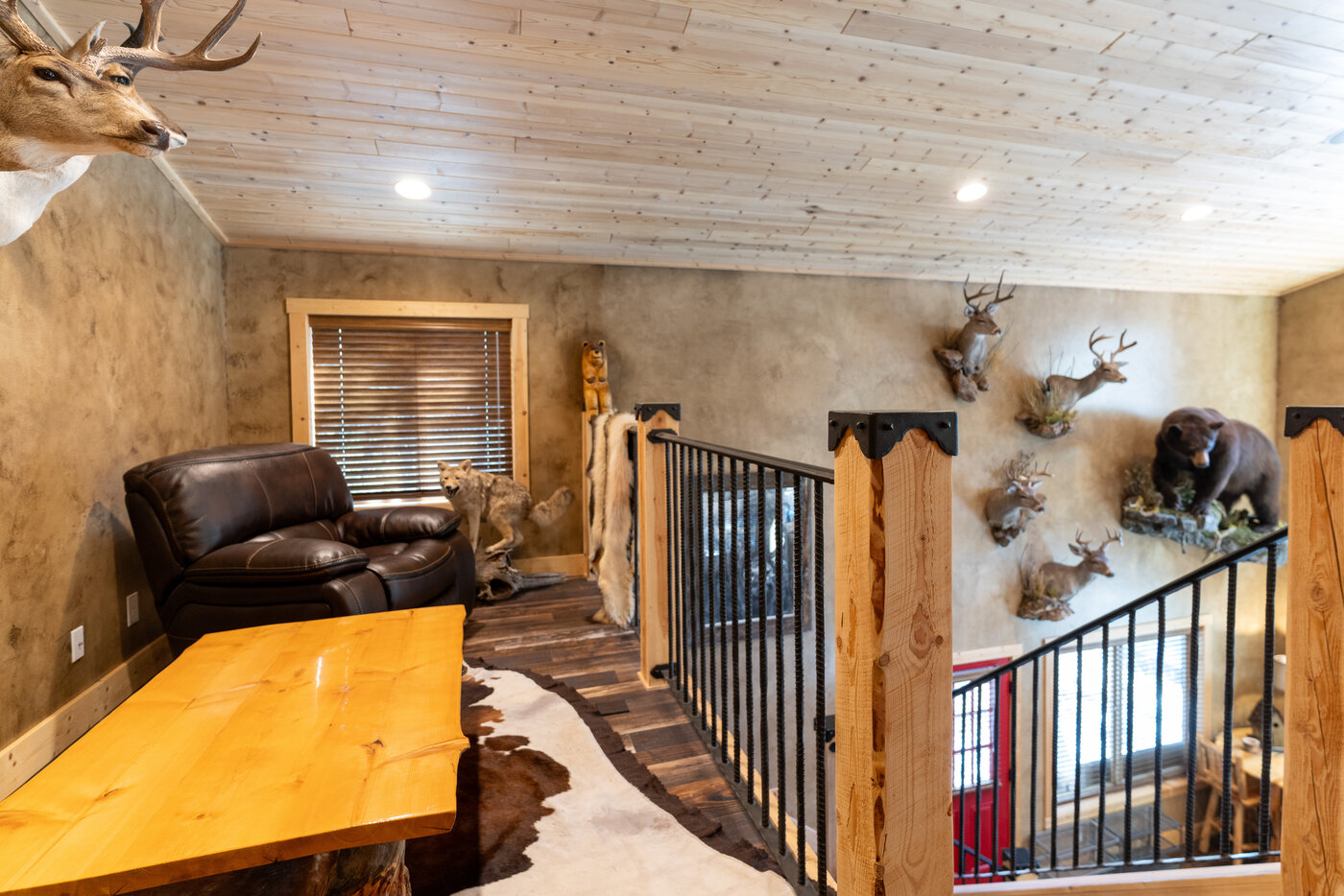 Trails End Lodge — second-floor seating area with leather club chair, slab table, and full taxidermy wall
