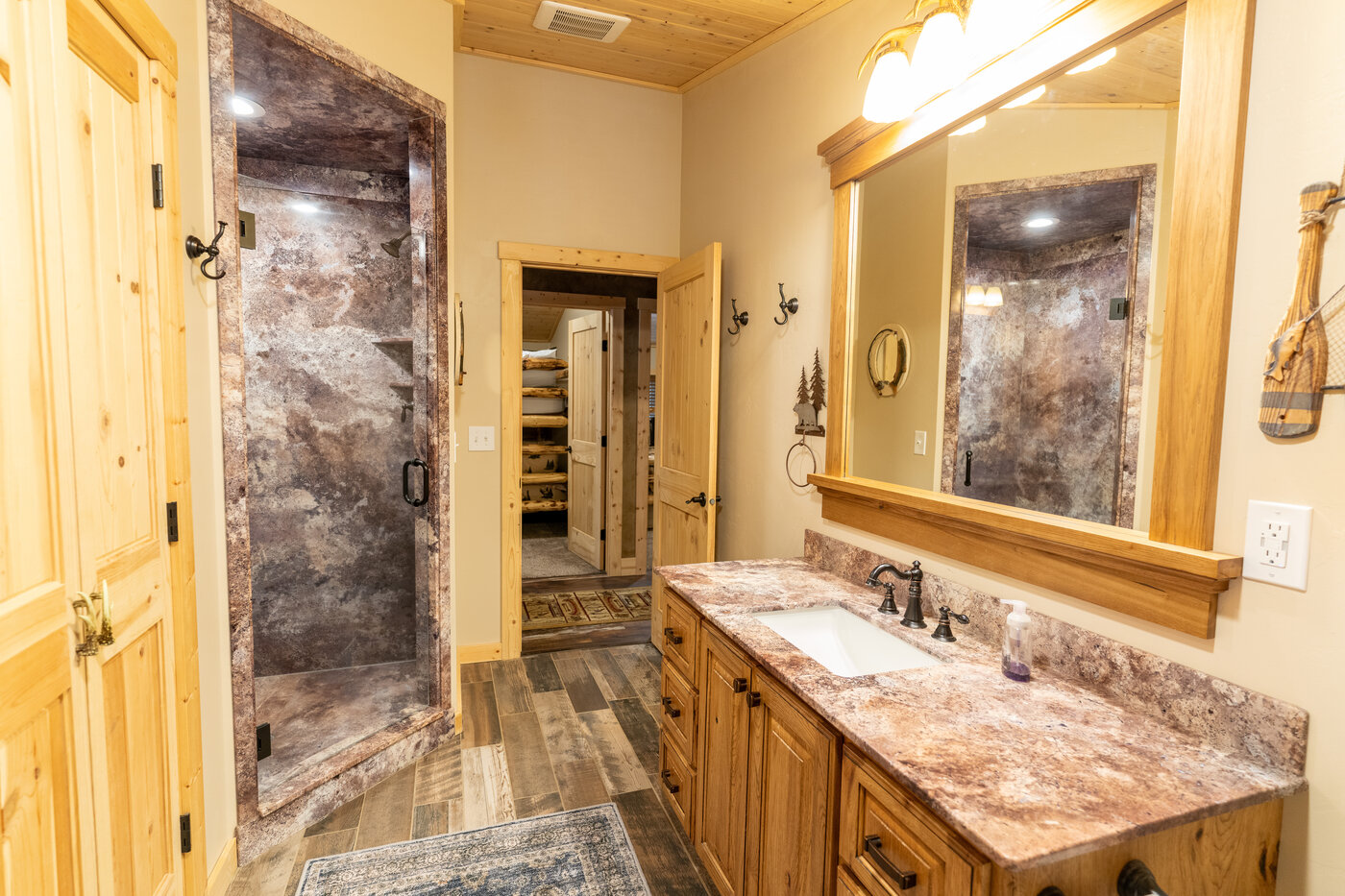 Trails End Lodge — bathroom with granite vanity, oak cabinets, and tile shower