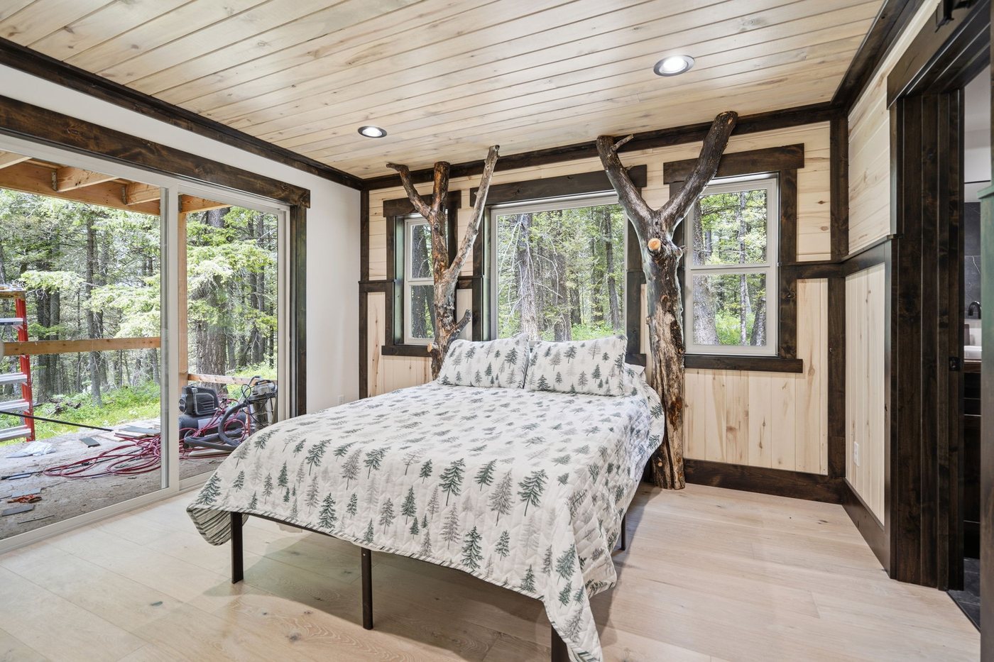 The Treehouse — bedroom with hand-built tree branch bed frame and forest windows