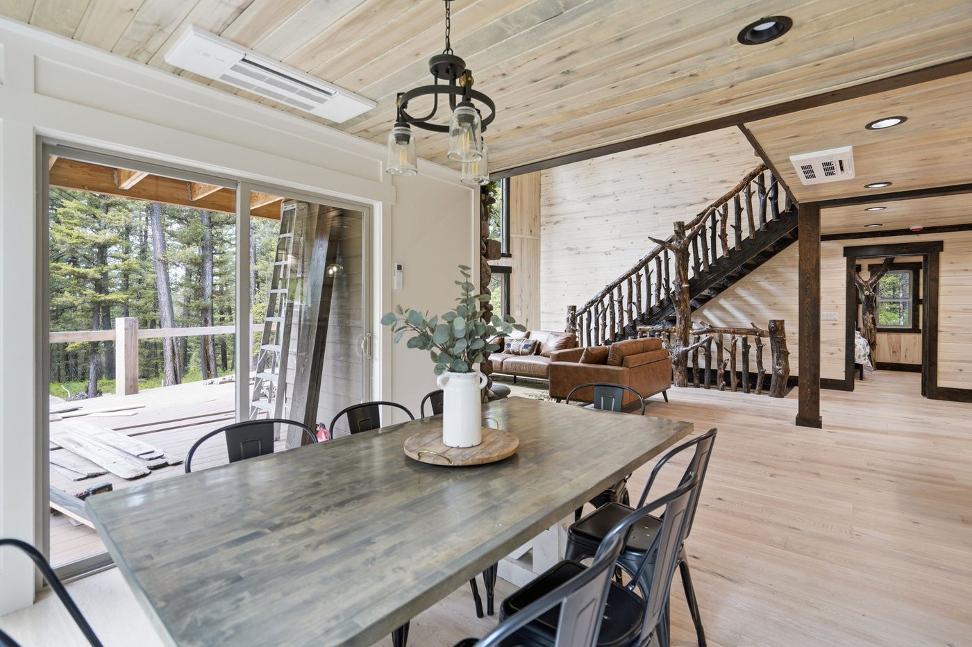 The Treehouse — dining table for the full group beside forest windows
